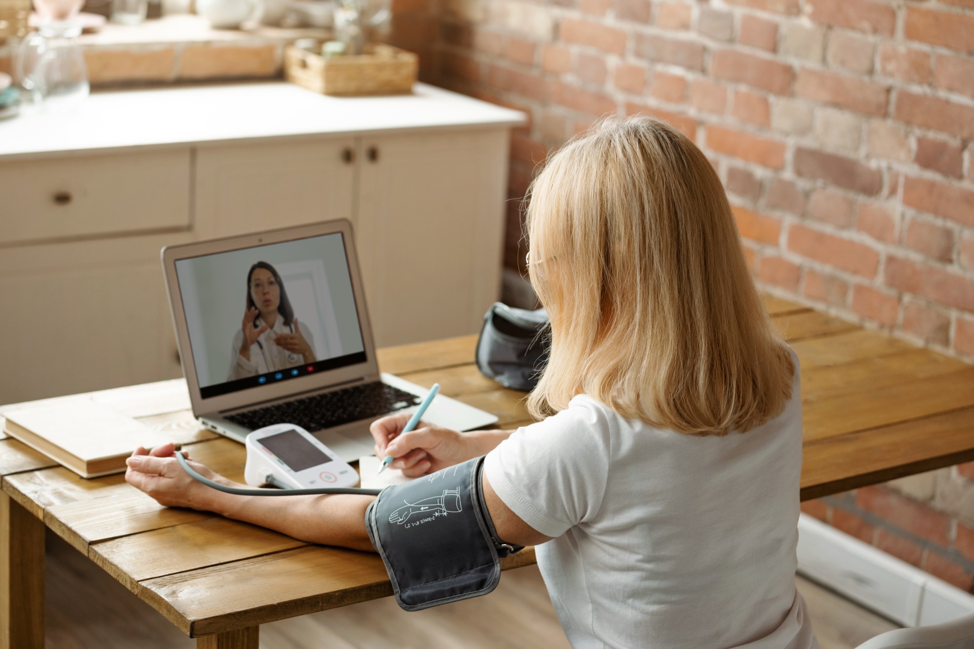 Person wearing a continuous glucose monitor on their arm while checking their smartphone in a kitchen