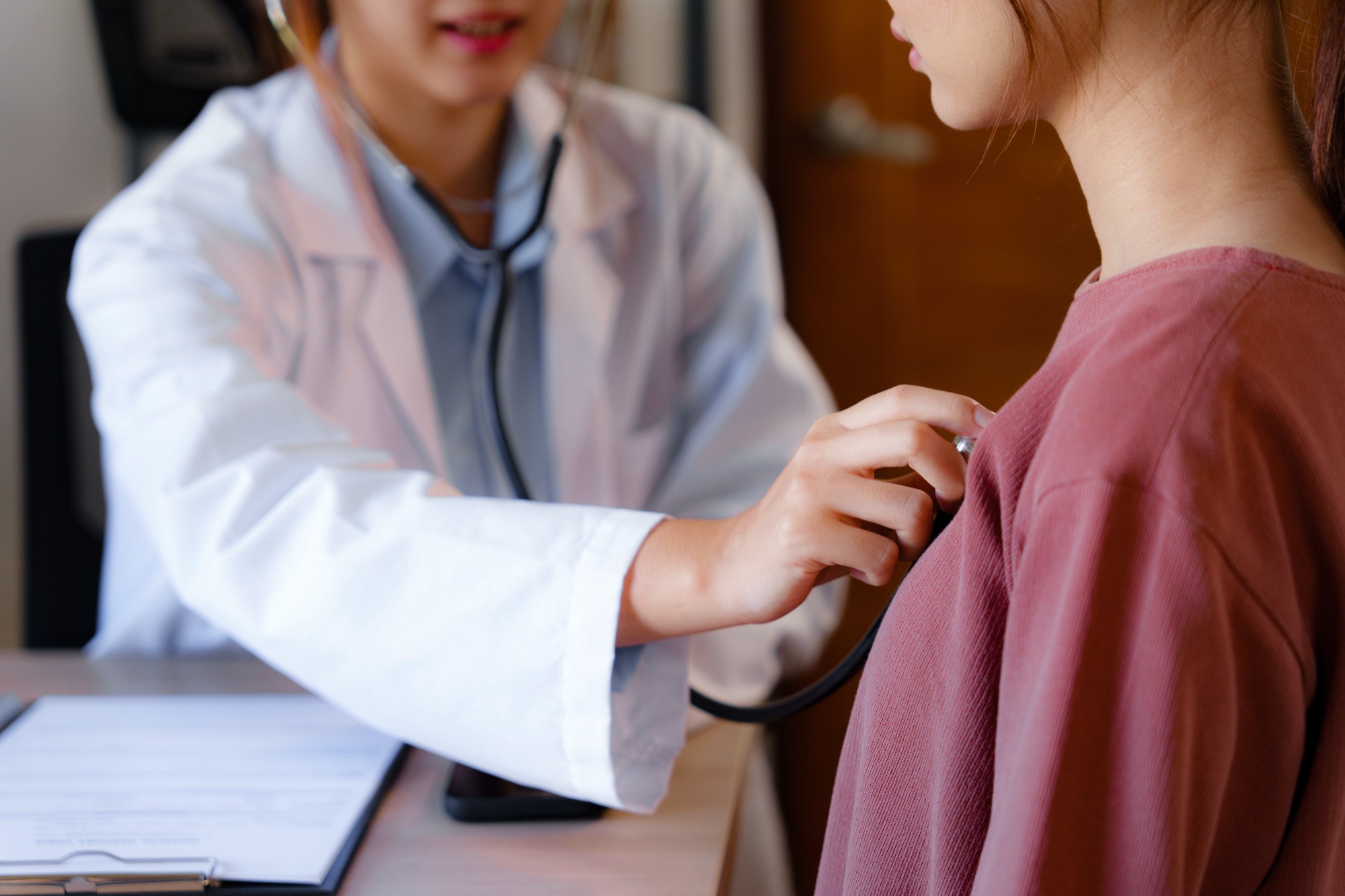 Doctor using a stethoscope to listen to a patient's heartbeat during a clinical visit
