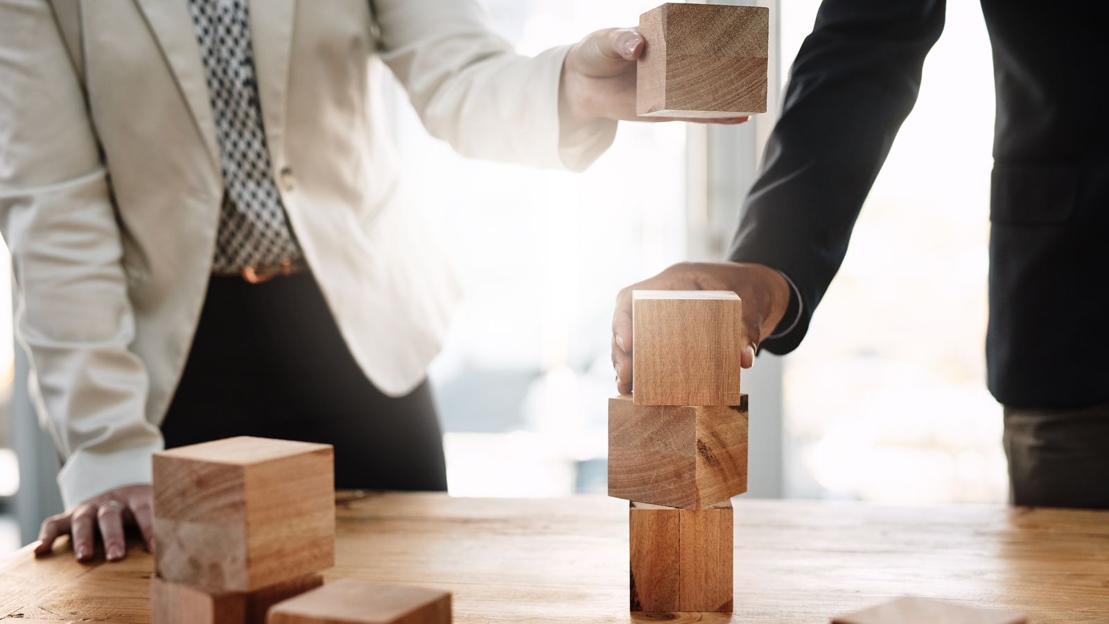 Business professionals stacking wooden blocks symbolizing teamwork and growth strategy