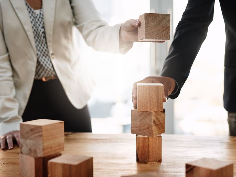 Business professionals stacking wooden blocks symbolizing teamwork and growth strategy