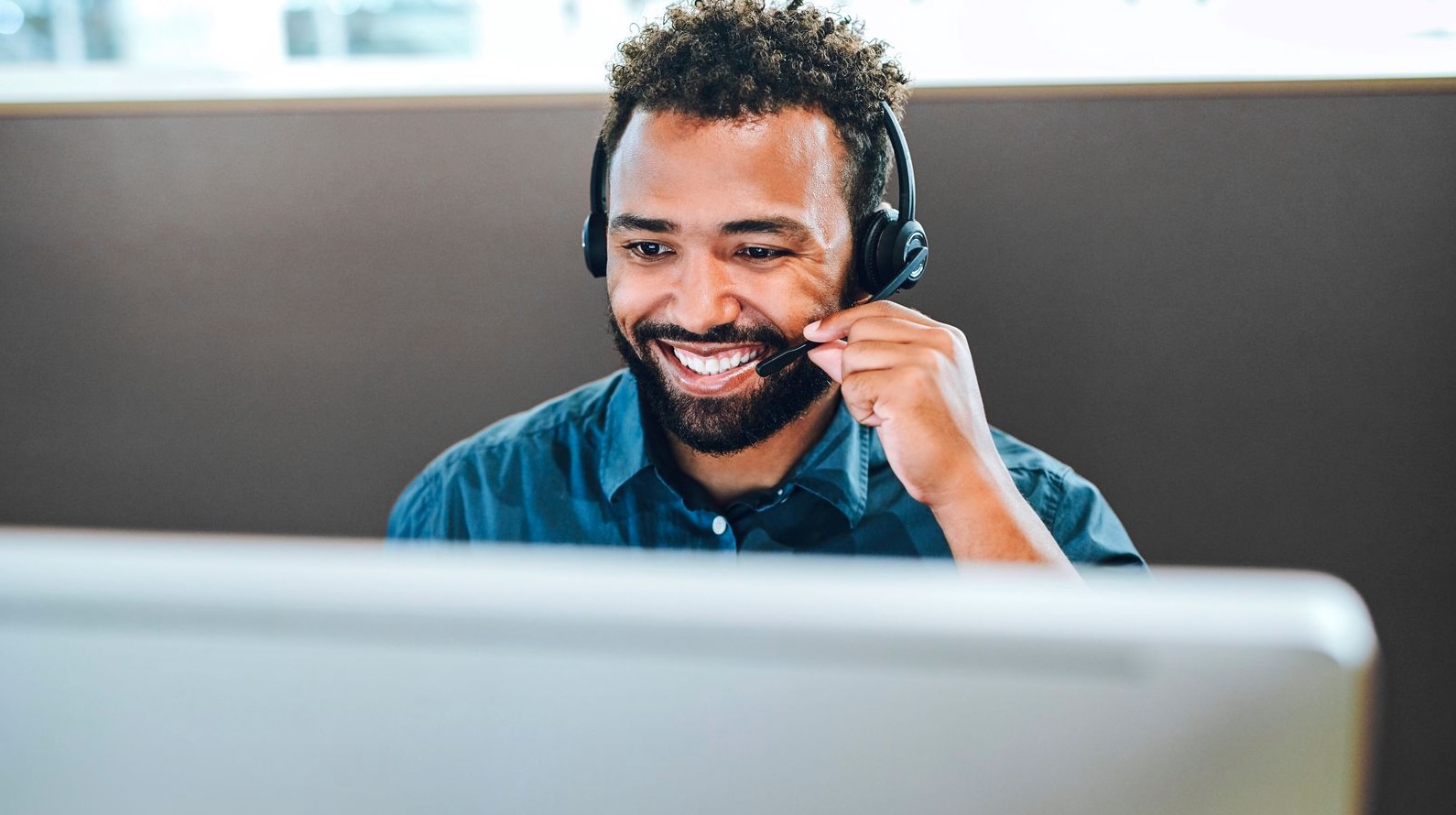 Smiling customer support representative wearing headset at desk