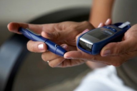 Close-up of hands holding a blood glucose meter and lancing device for diabetes testing.