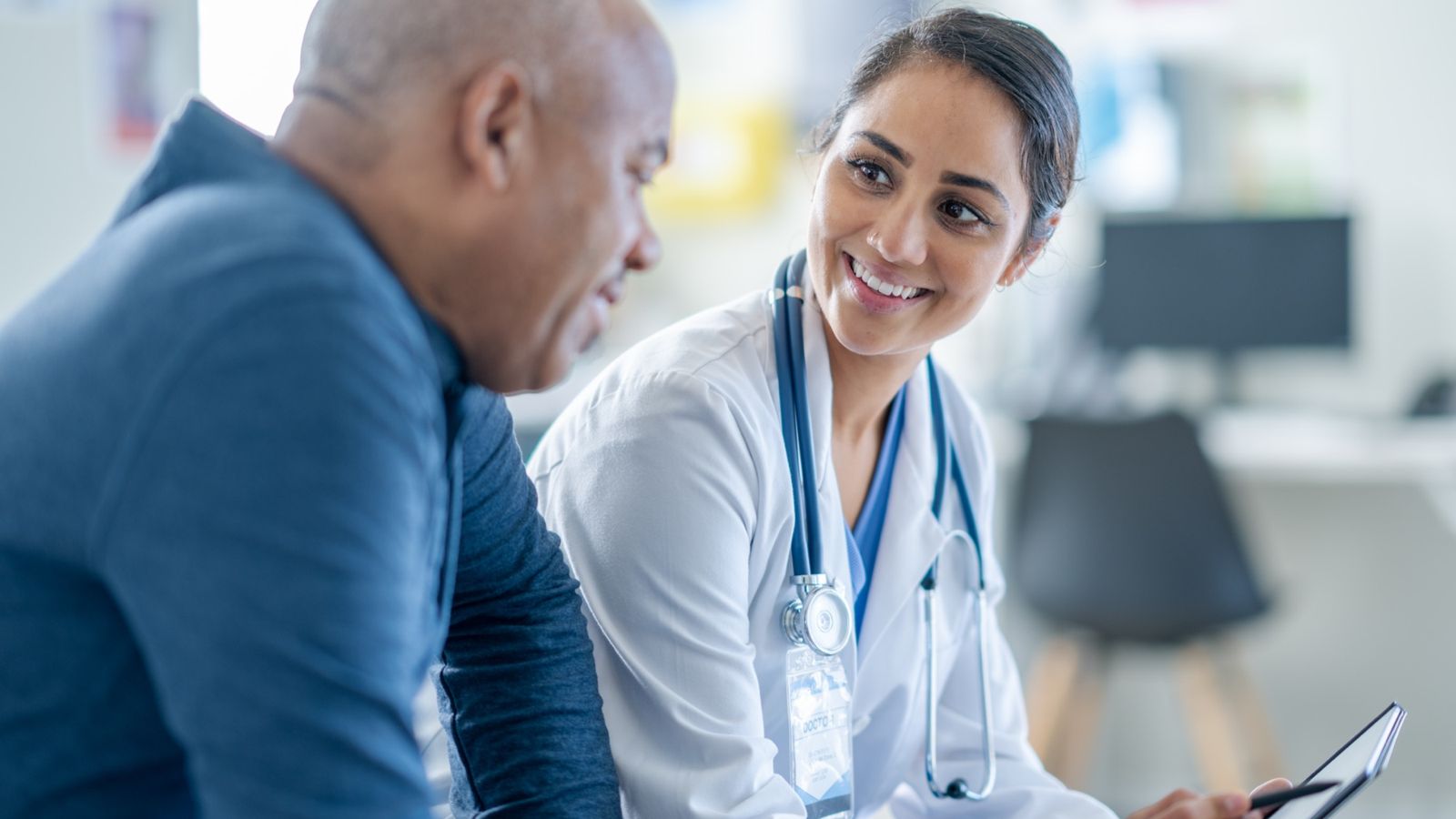 Doctor smiling and sharing information on a tablet with a senior male patient during a consultation