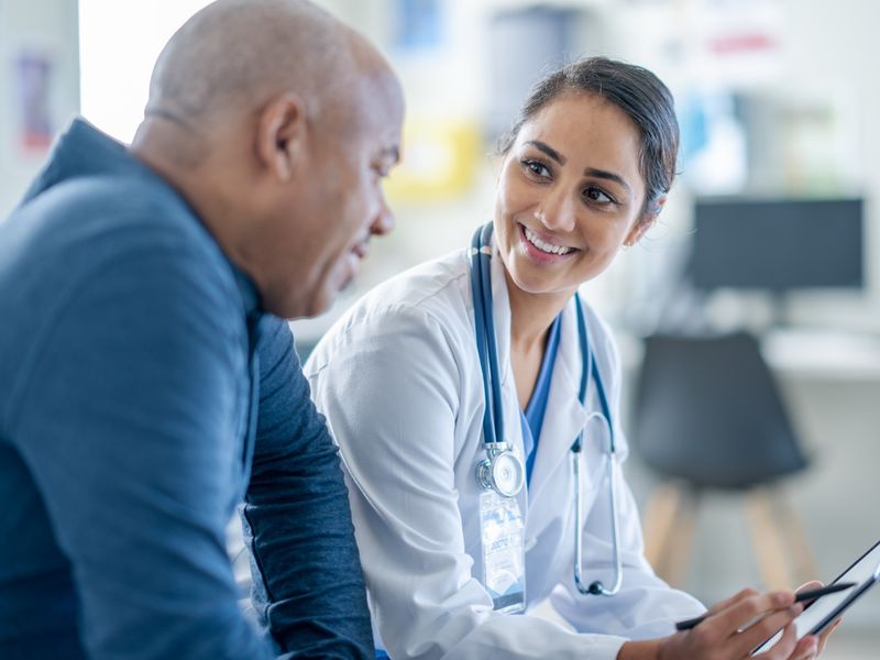 Doctor smiling and sharing information on a tablet with a senior male patient during a consultation