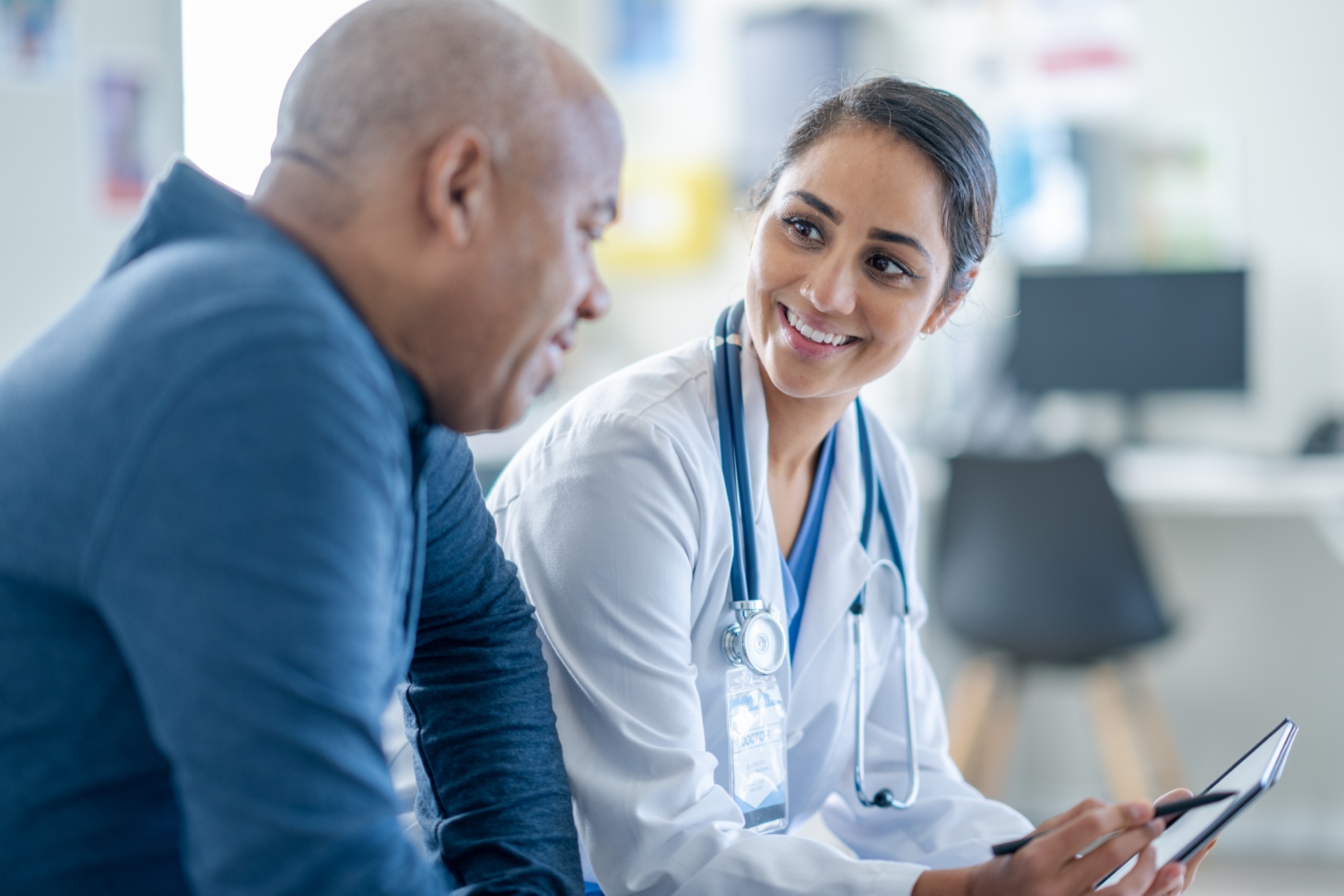 Doctor smiling and sharing information on a tablet with a senior male patient during a consultation