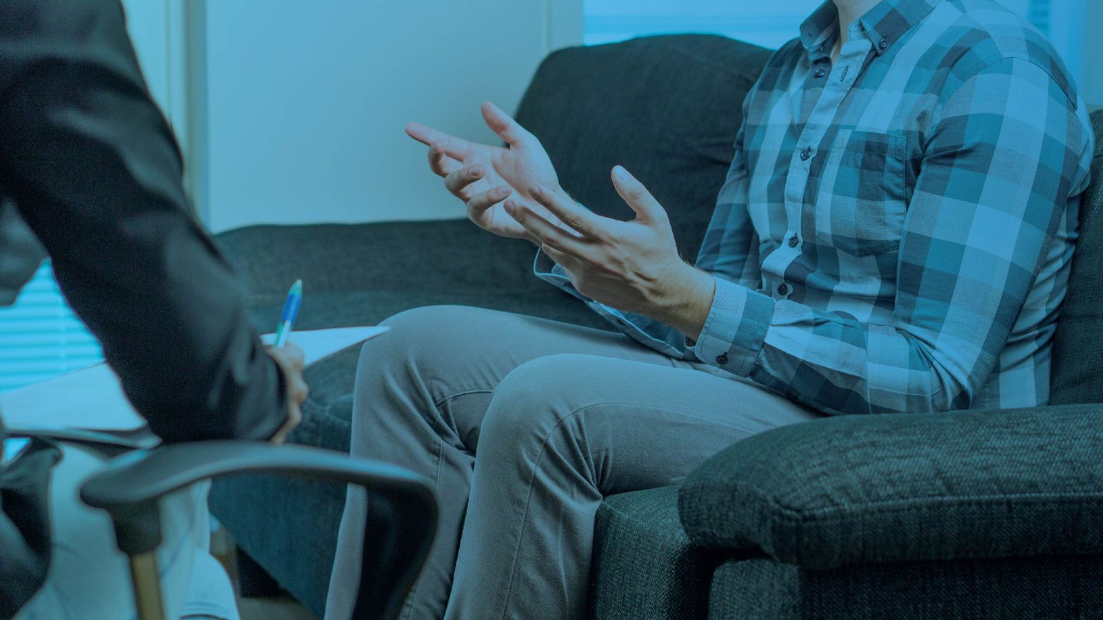 Person sitting on a couch gesturing during a counseling or therapy session, with a blue color overlay.