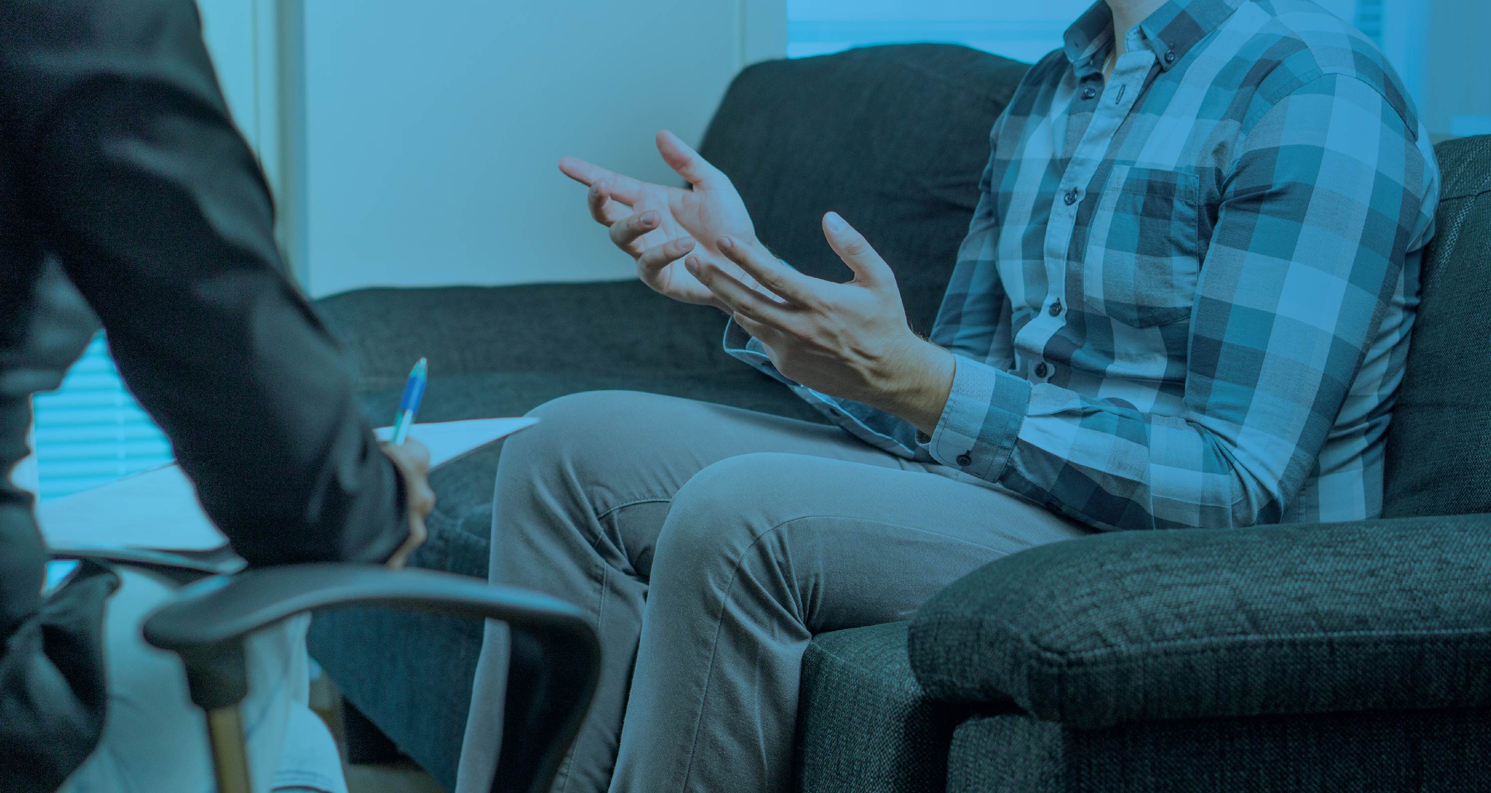 Person sitting on a couch gesturing during a counseling or therapy session, with a blue color overlay.