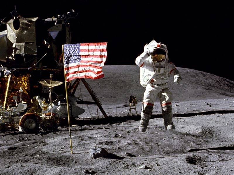 NASA astronaut saluting the American flag on the lunar surface with the lunar module and rover in the background.