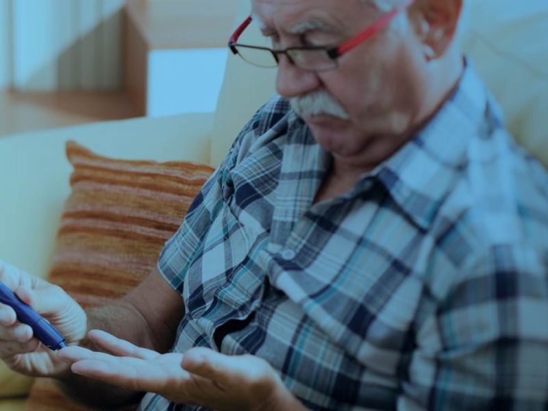 Senior man using a lancet device to test his blood sugar at home, with a blue-tinted overlay.