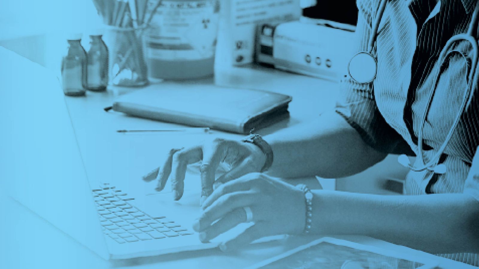 Healthcare professional with a stethoscope typing on a laptop at a desk, with a blue tint overlay.