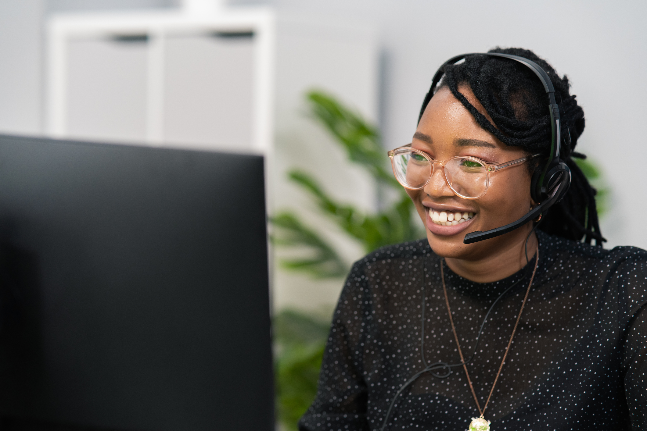 Smiling woman wearing a headset at a computer providing customer support.