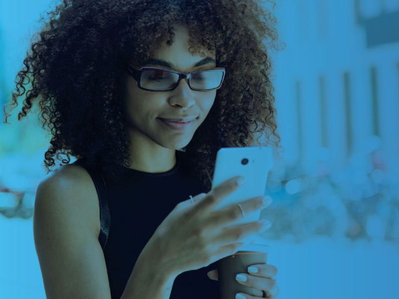 Young woman smiling while looking at her smartphone, with a blue overlay.