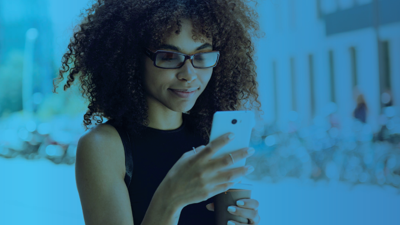 Young woman smiling while looking at her smartphone, with a blue overlay.