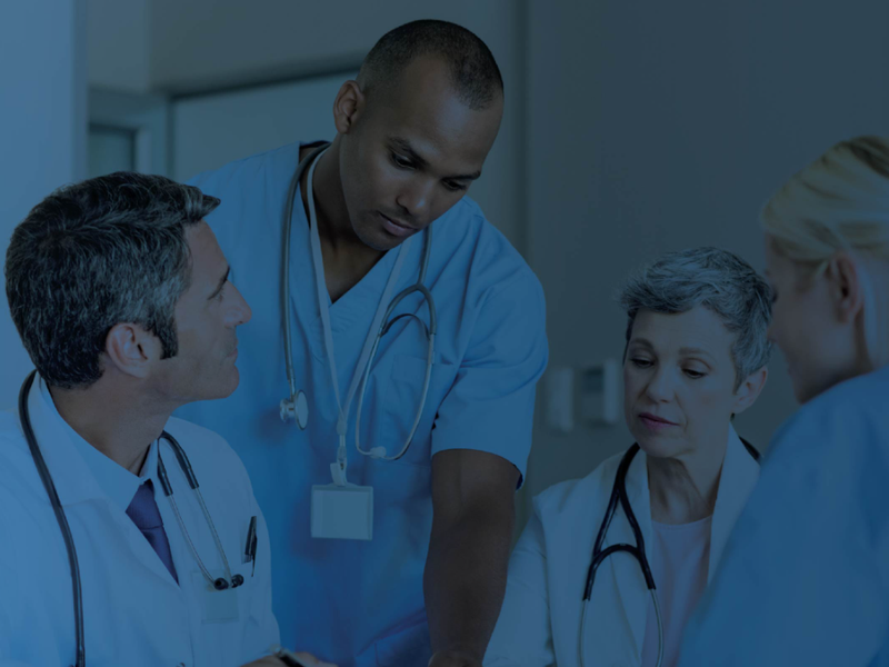 Group of healthcare professionals in scrubs having a discussion, with a blue overlay.